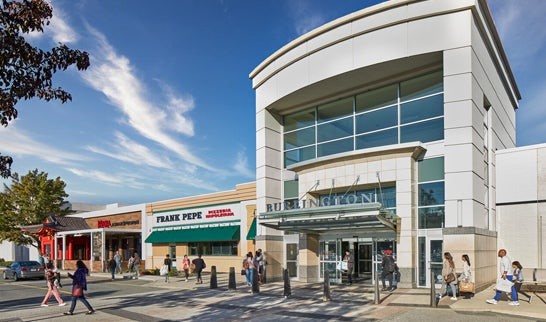 Exterior view of Burlington Mall featuring Burlington Coat Factory and Frank Pepe Pizzeria, with shoppers walking outside on a sunny day.