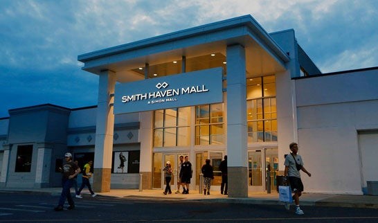 Smith Haven Mall entrance during evening hours, highlighting the mall's modern architecture and shoppers arriving for Black Friday 2024.