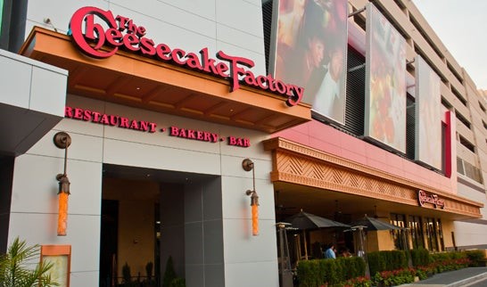 The Cheesecake Factory restaurant entrance at Arundel Mills Mall, featuring its signature signage with "Restaurant - Bakery - Bar" and an inviting outdoor seating area.